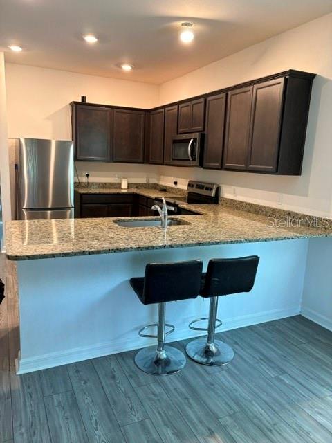 A kitchen features dark wood cabinets, granite countertops, a stainless steel refrigerator, and two barstools — 2119 NW 23RD TERRACE, CAPE CORAL, FL