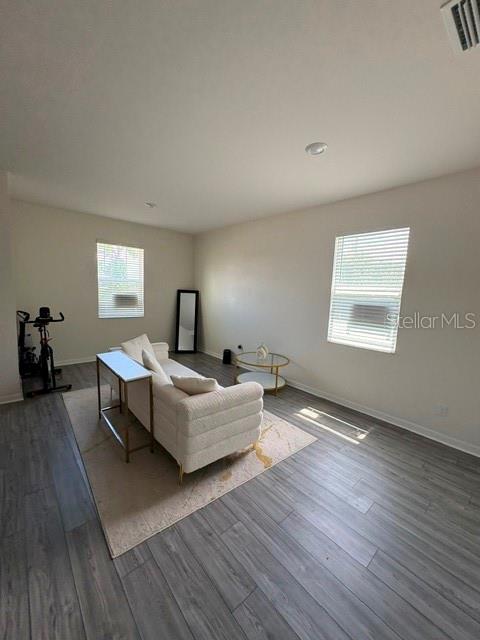 A living room features light-colored wood flooring, a white sofa, and two windows with blinds — 2119 NW 23RD TERRACE, CAPE CORAL, FL