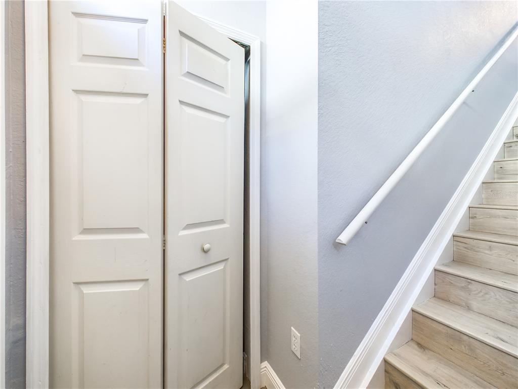A white bi-fold closet door sits next to a staircase with light wood-look steps — 5521 ROSEHILL ROAD UNIT 203, SARASOTA, FL