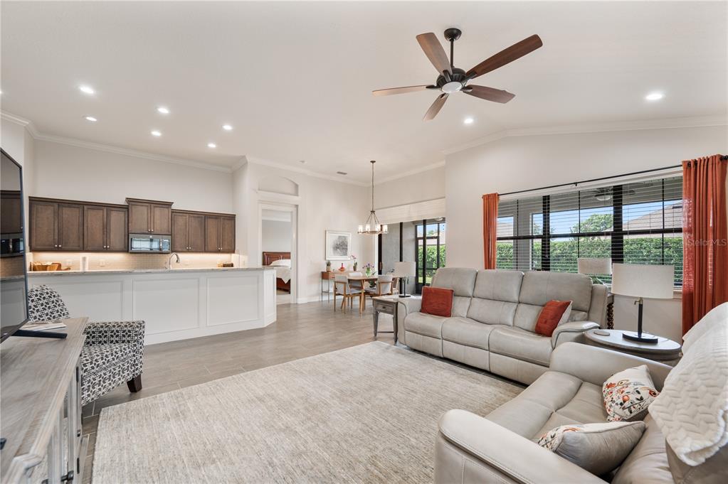 A living room with light gray sofas, a large area rug, and an open kitchen — 7783 LAKE JAMES BOULEVARD, LAKELAND, FL