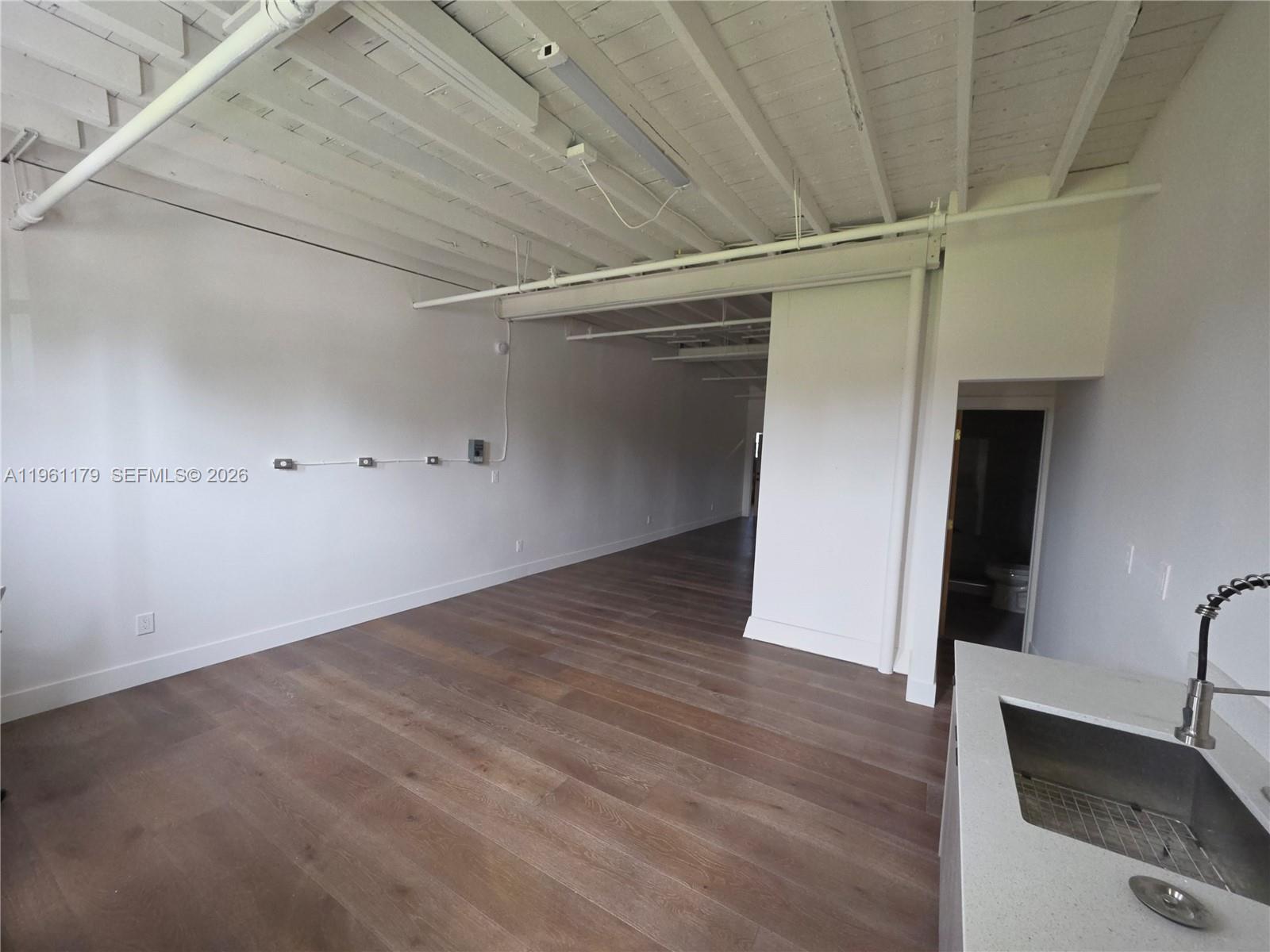 An open-concept room features white walls, exposed ceiling joists, wood flooring, and a small kitchenette — 164 NW 20th St # 202, Miami FL 33127, MIAMI, FL