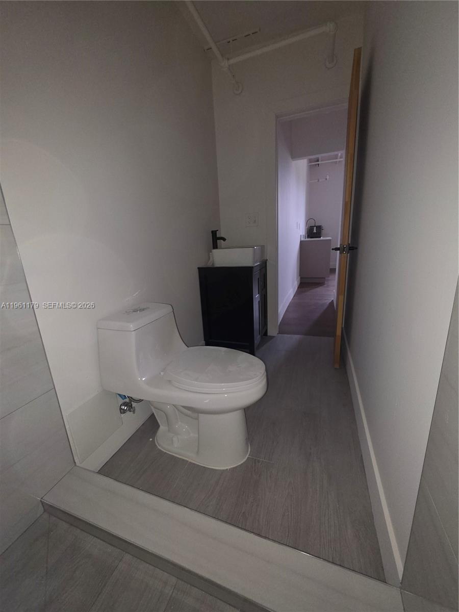 A small bathroom features a white toilet, a dark vanity with a vessel sink, and gray flooring — 164 NW 20th St # 202, Miami FL 33127, MIAMI, FL