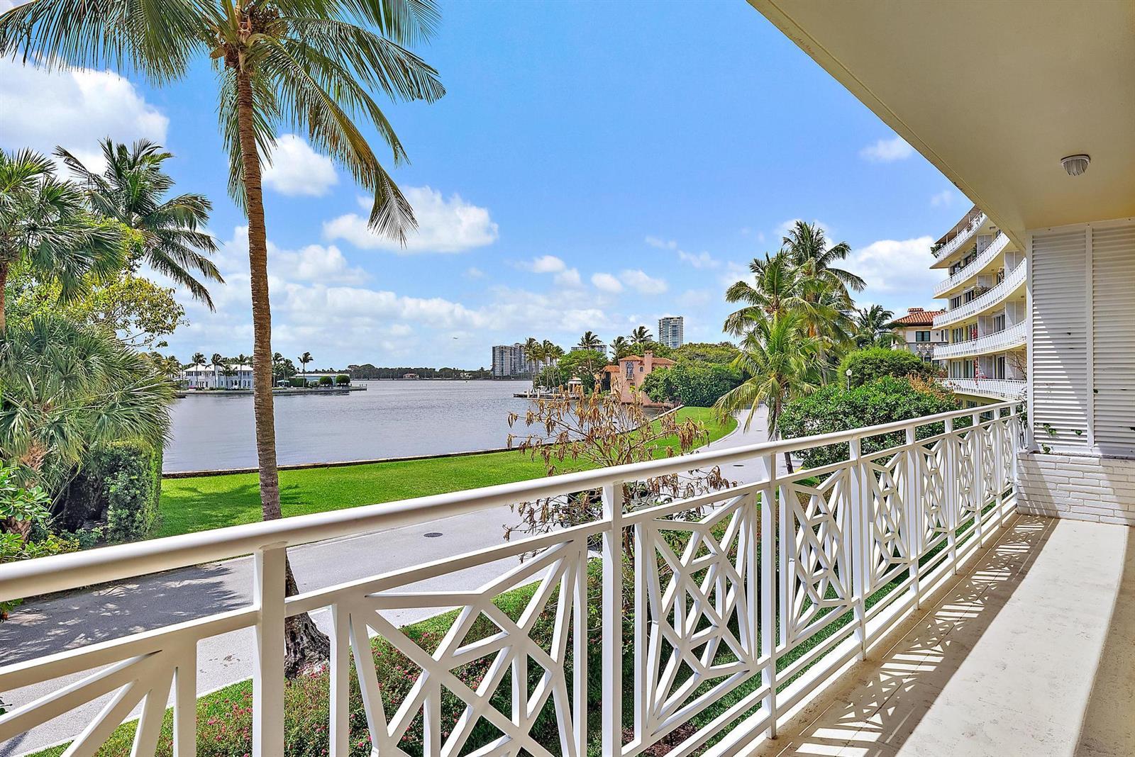 A balcony with a white lattice railing overlooks a grassy lawn, a road, and a lake — 425 Worth Avenue # 2f, Palm Beach FL 33480, PALM BEACH, FL