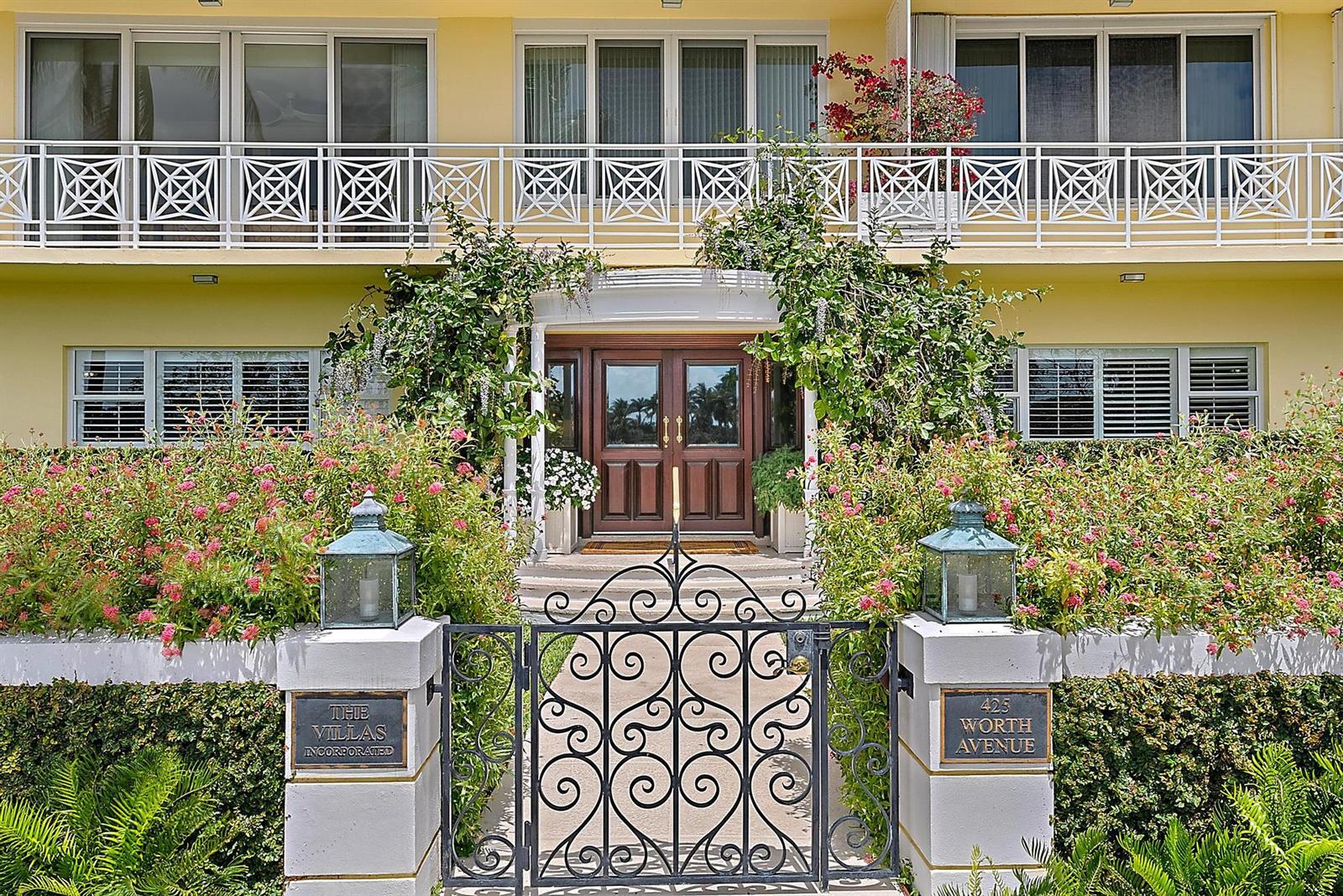 A gated entrance with a wooden door leads to a yellow building with balconies — 425 Worth Avenue # 2f, Palm Beach FL 33480, PALM BEACH, FL