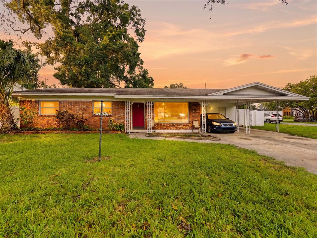 A single-story brick house with a front porch, carport, and a large lawn at sunset — 2109 W ERNA DRIVE, TAMPA, FL