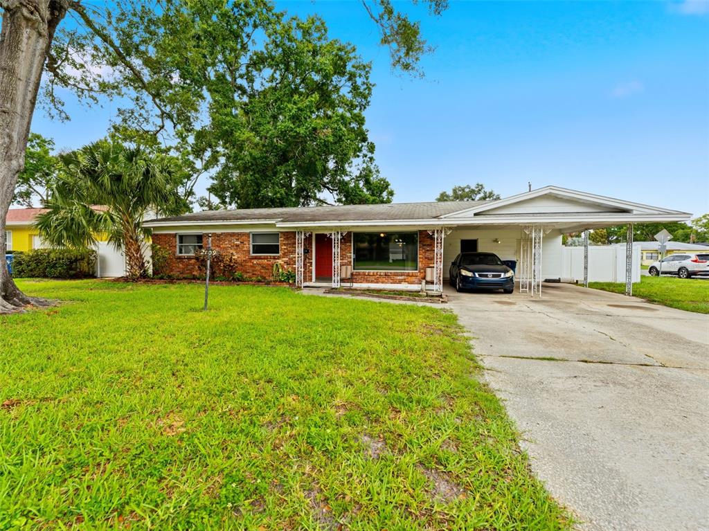 A single-story brick house features a front lawn, a carport, and a red front door — 2109 W ERNA DRIVE, TAMPA, FL