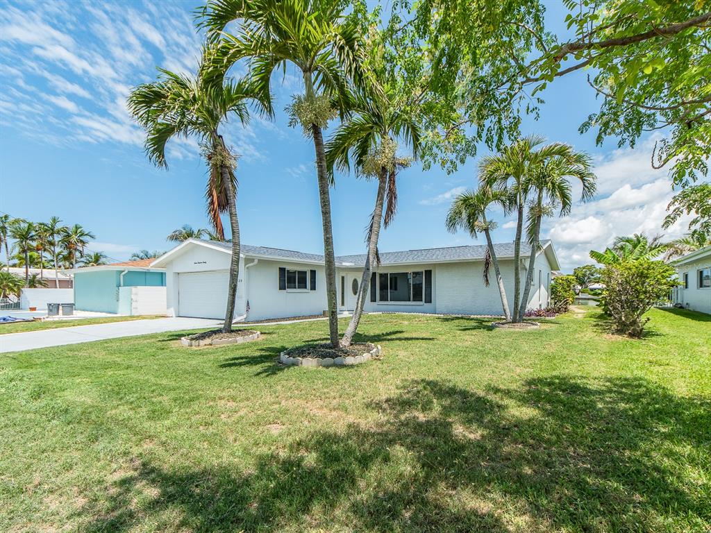 A single-story white house with a garage and palm trees in the front yard — 720 115TH AVENUE, TREASURE ISLAND, FL