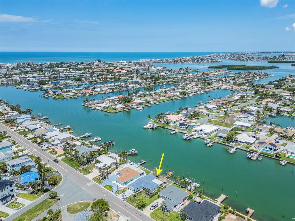 An aerial view shows a waterfront house with a dock and boat lift on a canal — 720 115TH AVENUE, TREASURE ISLAND, FL