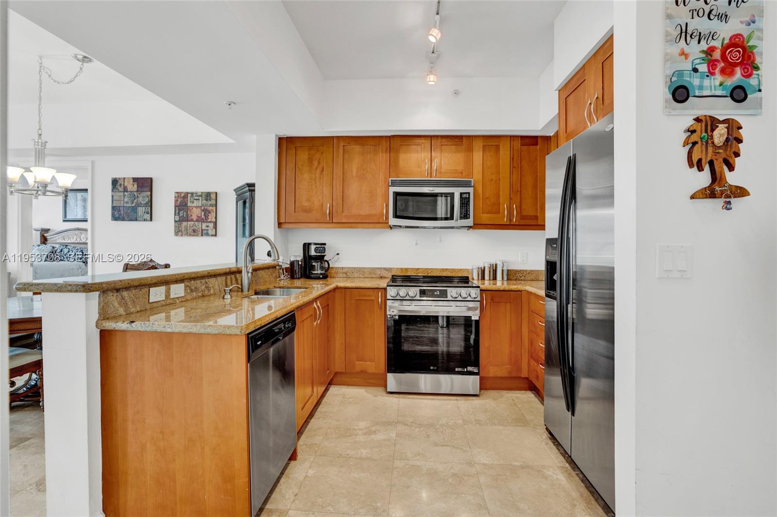 A kitchen features wood cabinets, granite countertops, stainless steel appliances, and tile flooring — 1755 E Hallandale Beach Blvd # 1208E, Hallandale Beach FL 33009, HALLANDALE BEACH, FL