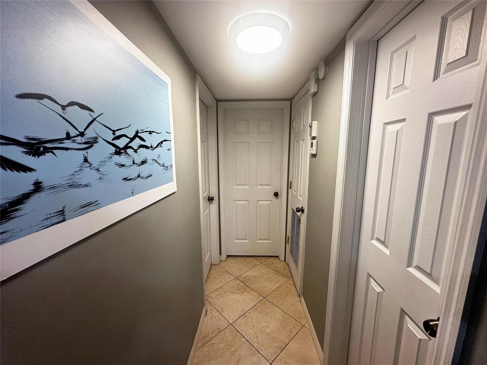 A hallway with tile flooring, white doors, and a large bird-themed wall print — 2400 S Ocean Drive # 314, Hollywood FL 33019, HOLLYWOOD, FL