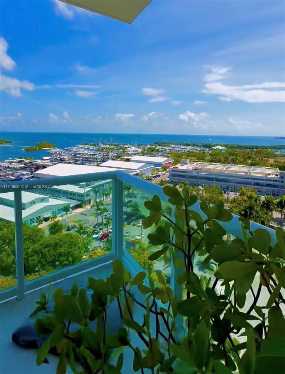 A balcony view overlooking a marina, parking structures, and the ocean under a blue sky — 2645 S Bayshore Dr # 1403, Miami FL 33133, MIAMI, FL
