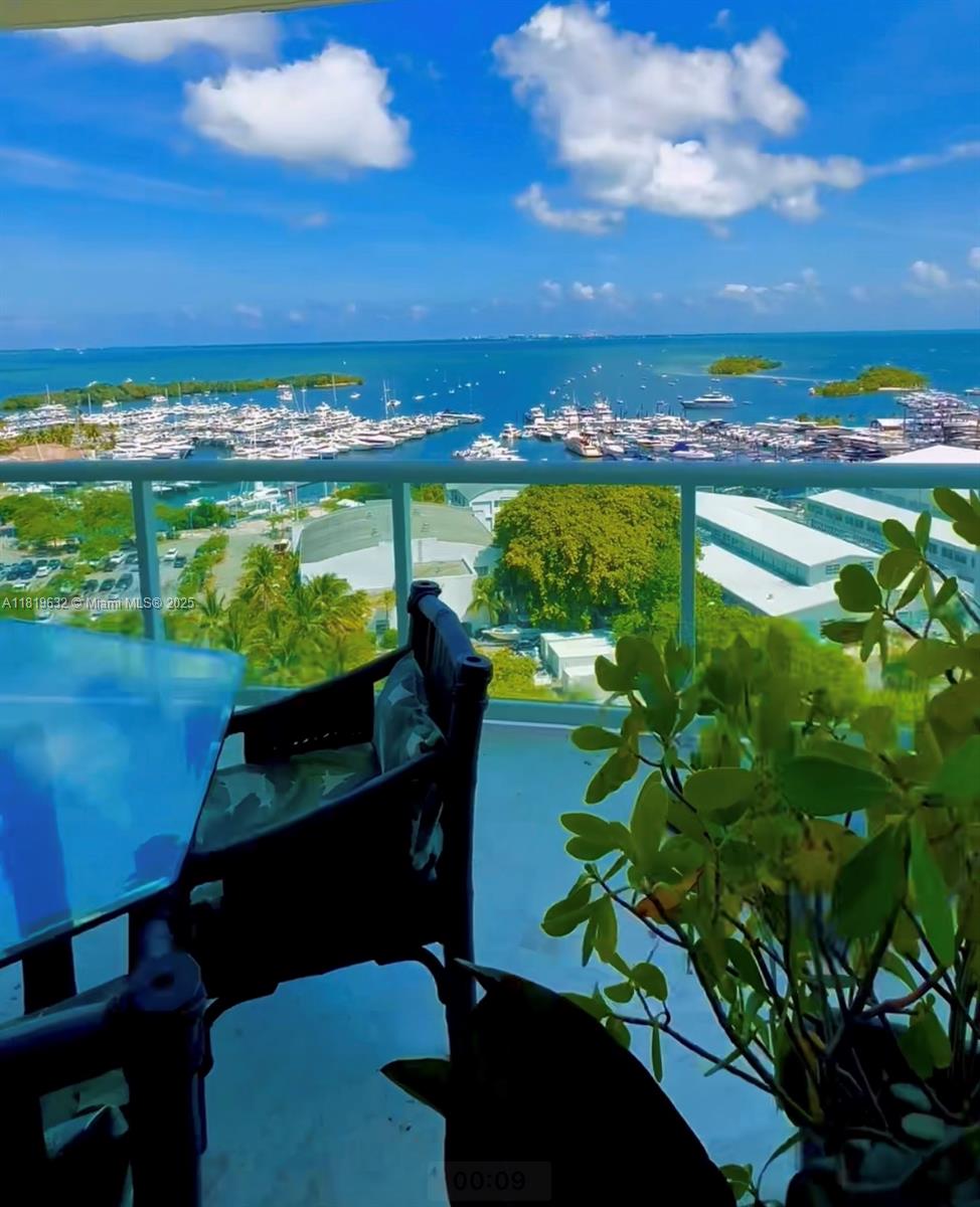 A balcony view overlooks a marina filled with boats and the ocean under a blue sky — 2645 S Bayshore Dr # 1403, Miami FL 33133, MIAMI, FL