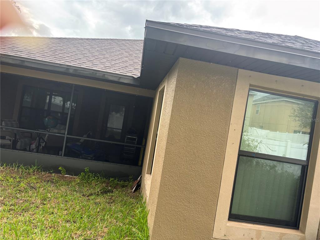 A view of a house exterior showing a screened-in porch and a single window — 12214 LEGACY BRIGHT, RIVERVIEW, FL