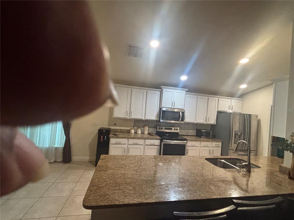 A kitchen features white cabinets, granite countertops, a center island, and stainless steel appliances — 12214 LEGACY BRIGHT, RIVERVIEW, FL