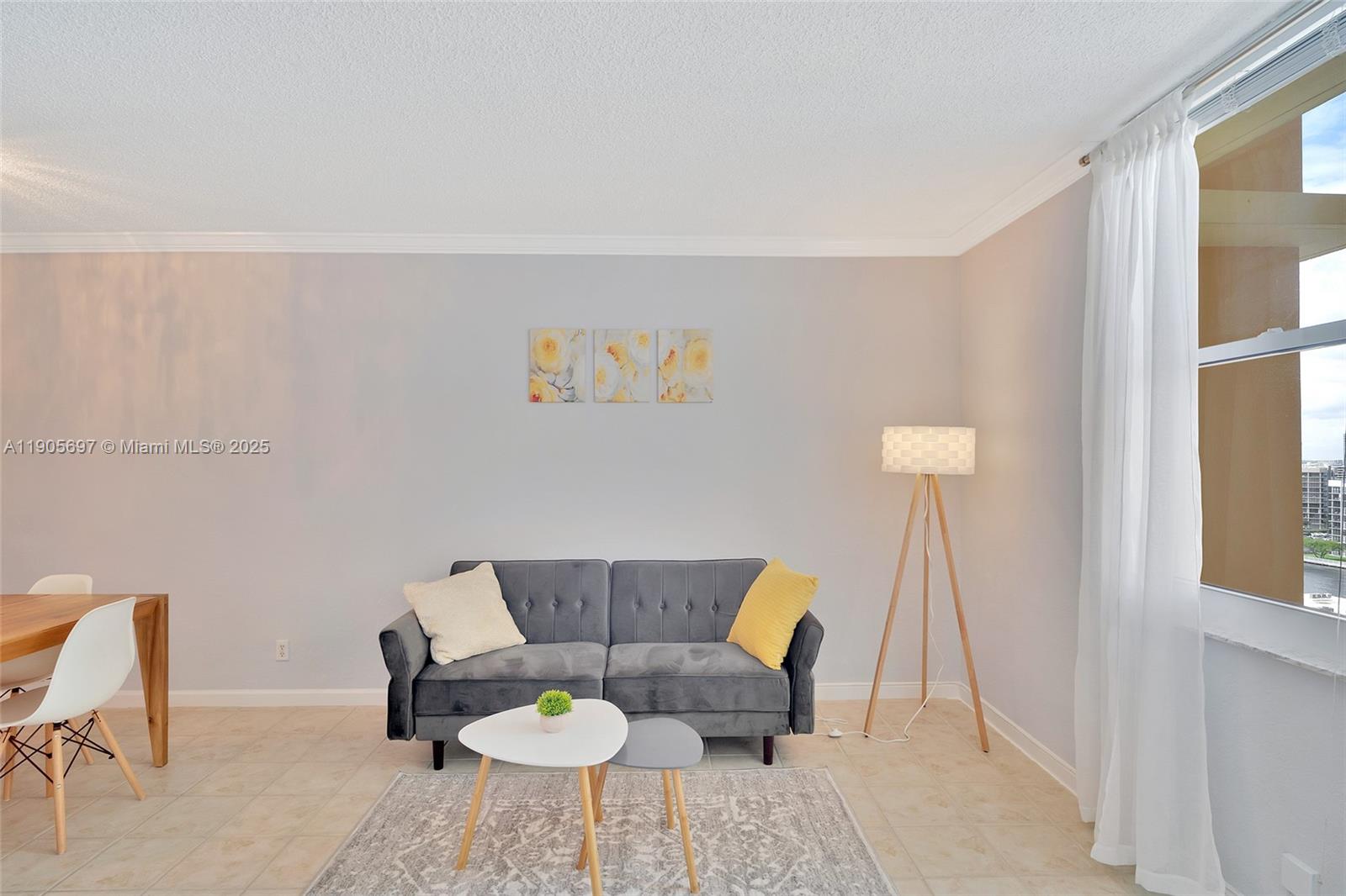 A living room features a grey sofa, nesting coffee tables, and a tripod floor lamp — 2501 S Ocean Dr # 1432, Hollywood FL 33019, HOLLYWOOD, FL