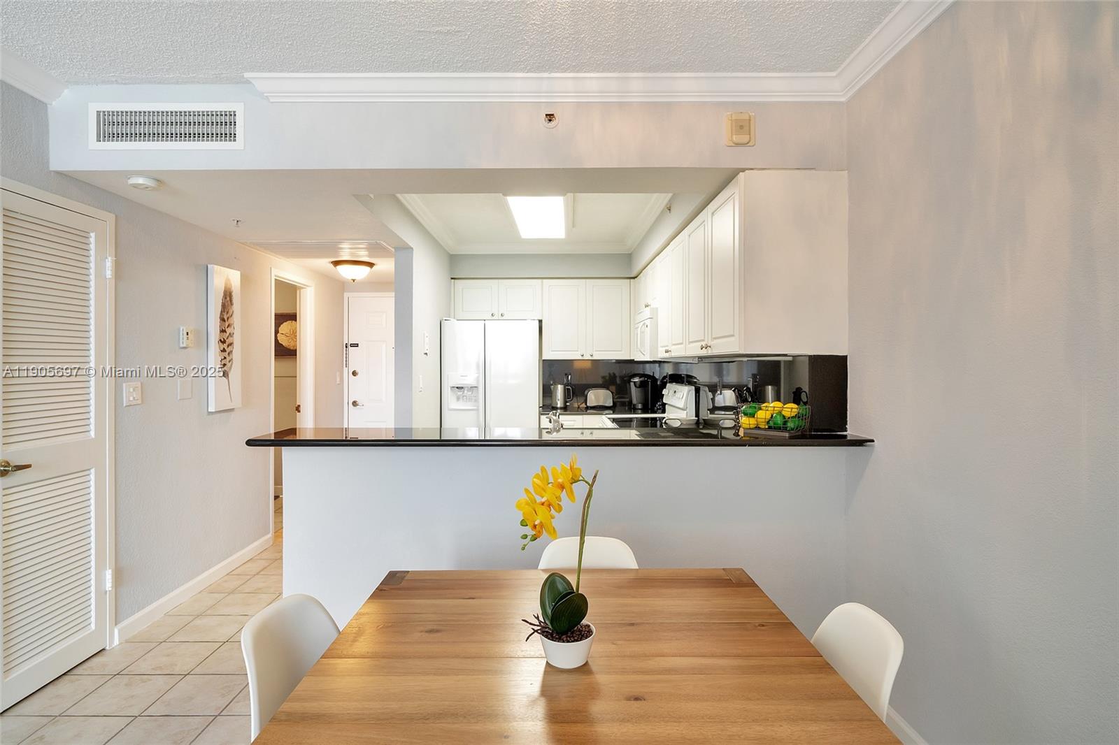 A dining area with a wooden table faces an open kitchen featuring white cabinets — 2501 S Ocean Dr # 1432, Hollywood FL 33019, HOLLYWOOD, FL