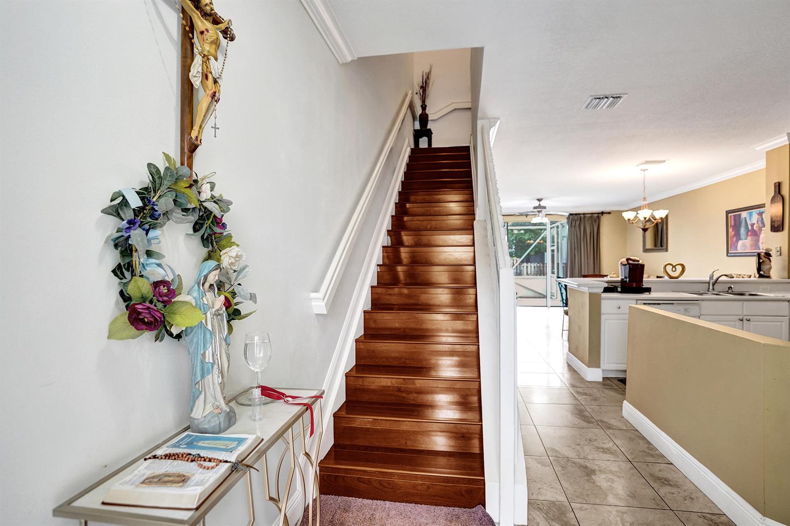 A wooden staircase leads to an upper floor beside a kitchen and entryway console table — 9664 Porta Leona Lane, Boynton Beach FL 33472, BOYNTON BEACH, FL