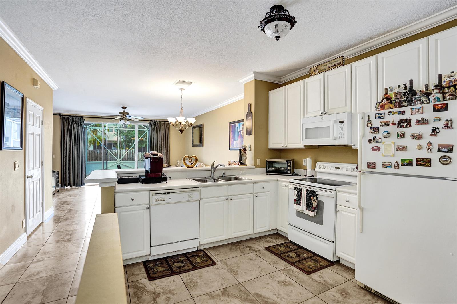 A kitchen features white cabinets, white appliances, tan walls, and tile flooring — 9664 Porta Leona Lane, Boynton Beach FL 33472, BOYNTON BEACH, FL