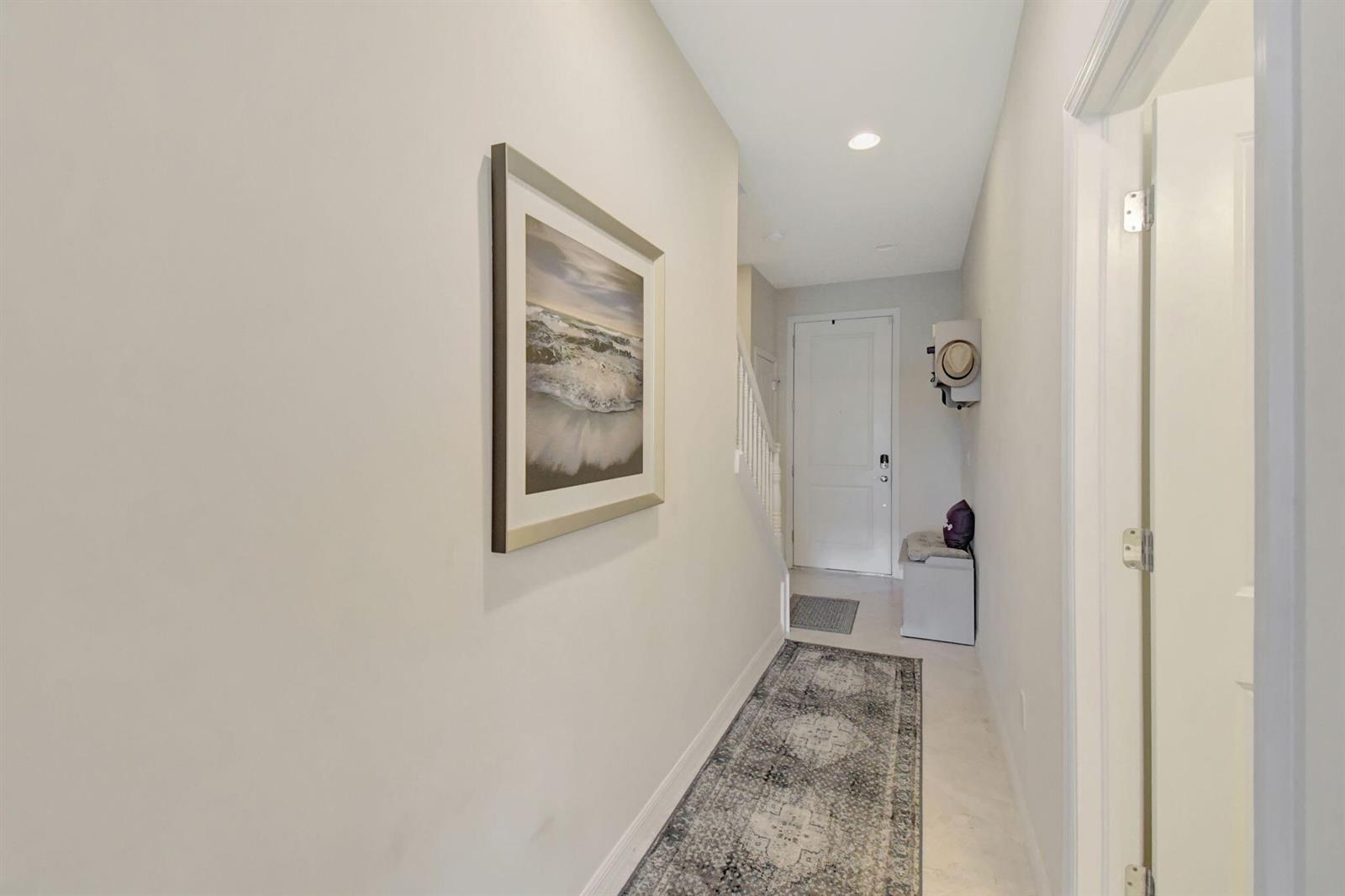 A hallway features a patterned runner rug, framed wall art, and a white entry door — 1105 Banyan Drive, Hollywood FL 33021, HOLLYWOOD, FL