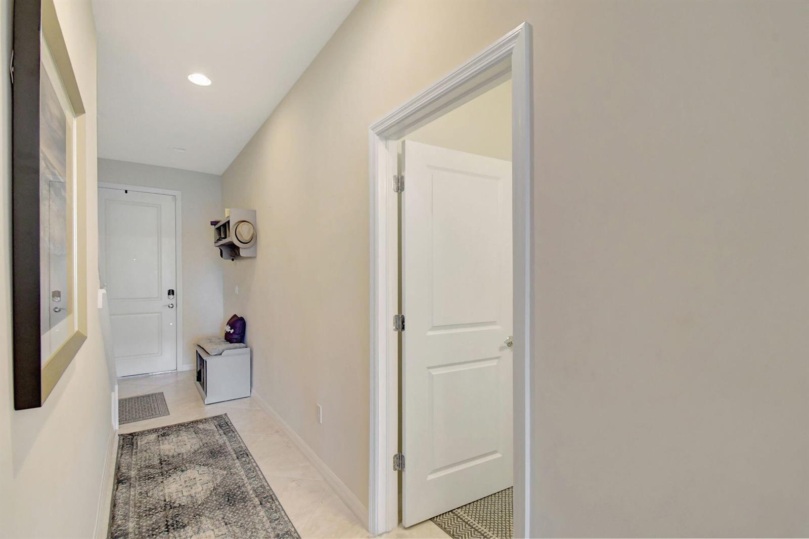 A hallway features a white door, a small storage bench, and a patterned area rug — 1105 Banyan Drive, Hollywood FL 33021, HOLLYWOOD, FL