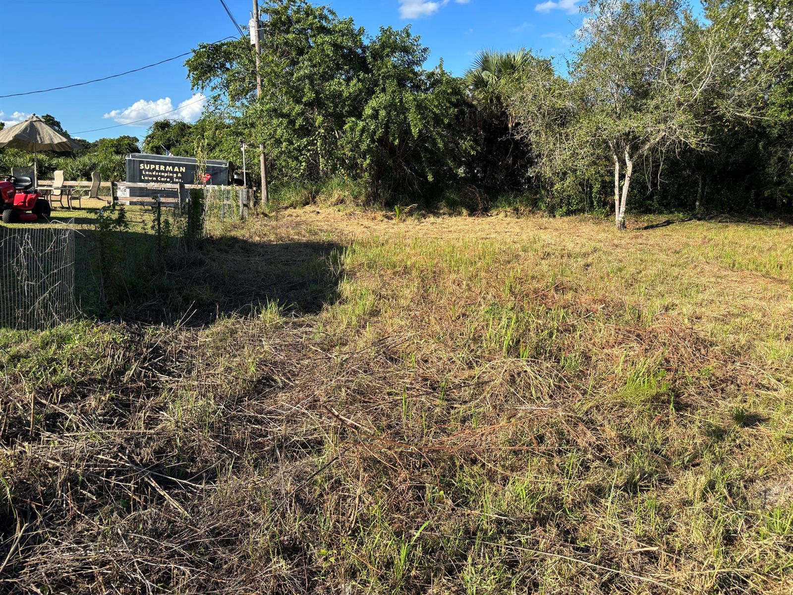 A large, grassy, undeveloped lot with trees and a fence in the background — 2897 NW 32nd Avenue, Okeechobee FL 34972, OKEECHOBEE, FL