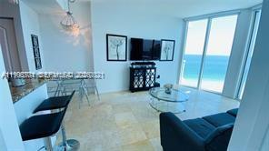 A living room with tile floors, a television, and a view of the ocean — 6515 Collins Ave # 1604, Miami Beach FL 33141, MIAMI BEACH, FL