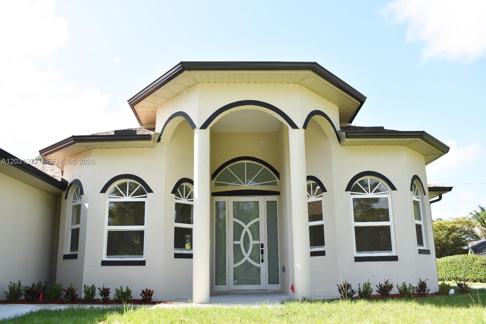 A single-story house exterior features a central arched entryway with columns and arched windows — 2515 45th st W, Lehigh Acres FL 33971, LEHIGH ACRES, FL