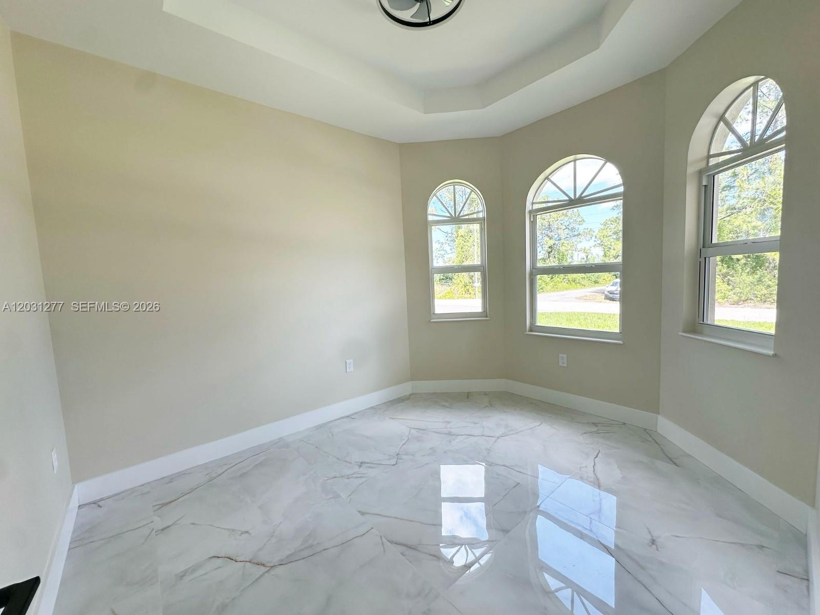 A room with beige walls, white marble-look flooring, and three arched windows — 2515 45th st W, Lehigh Acres FL 33971, LEHIGH ACRES, FL