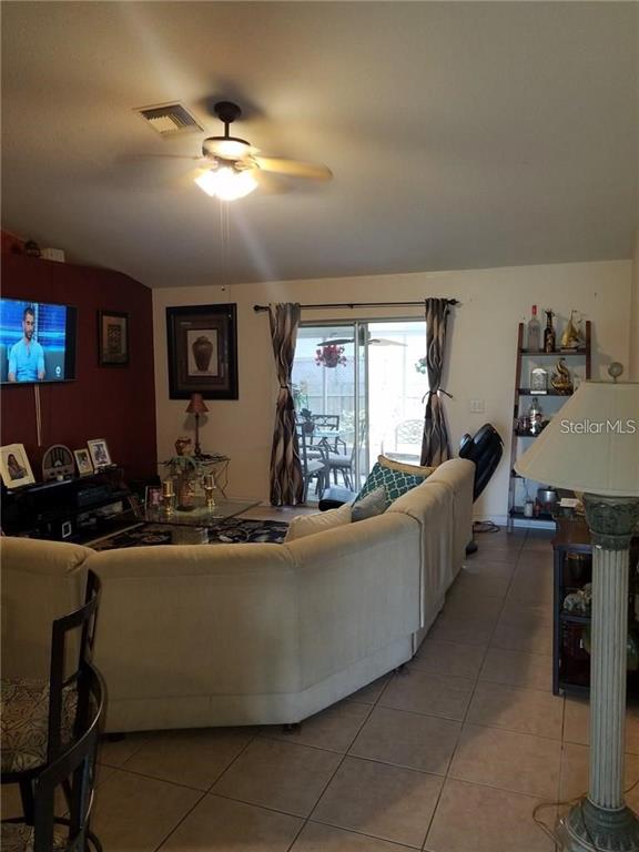 A living room features a large sectional sofa, a ceiling fan, and a sliding glass door — 3030 MUIR STREET, HOLIDAY, FL