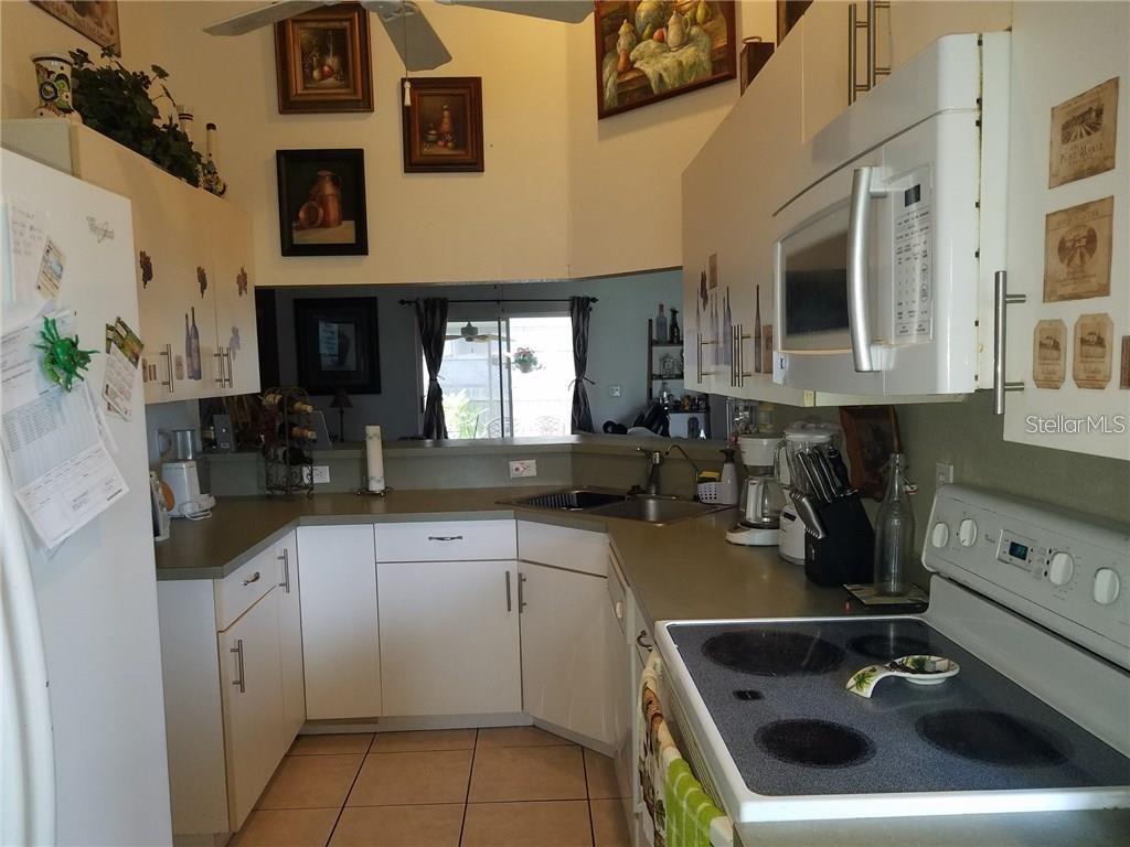 A kitchen with white cabinets, gray countertops, a white stove, and a microwave — 3030 MUIR STREET, HOLIDAY, FL