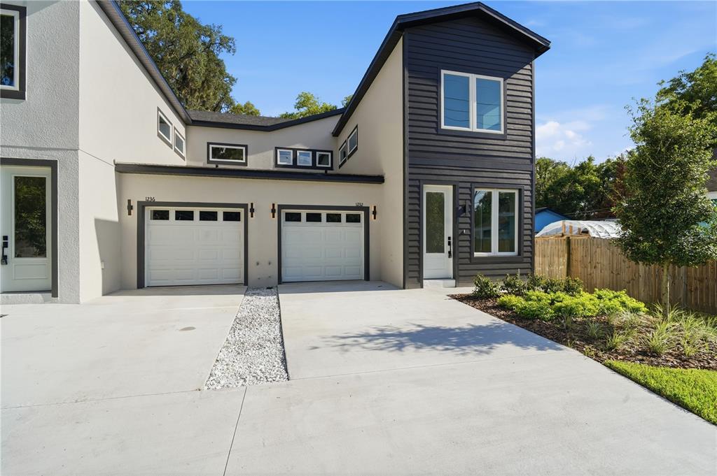 A modern two-story duplex with white stucco, dark siding, and two white garage doors — 1232 VIRGINIA DRIVE, ORLANDO, FL