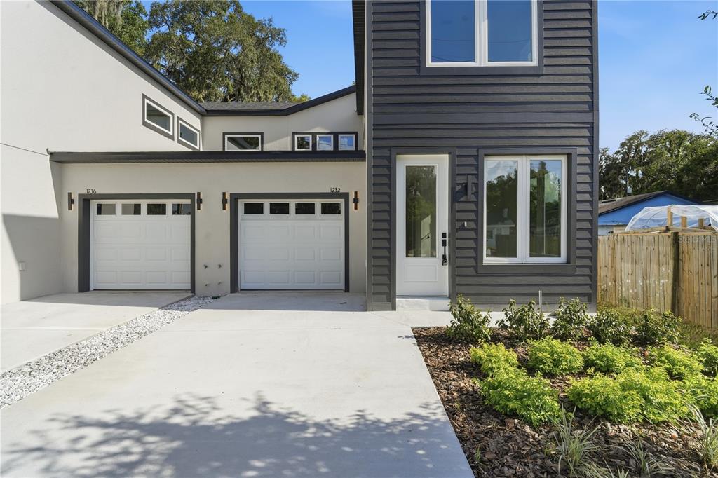 A modern two-story duplex with two garage doors, white stucco, and dark gray horizontal siding — 1232 VIRGINIA DRIVE, ORLANDO, FL