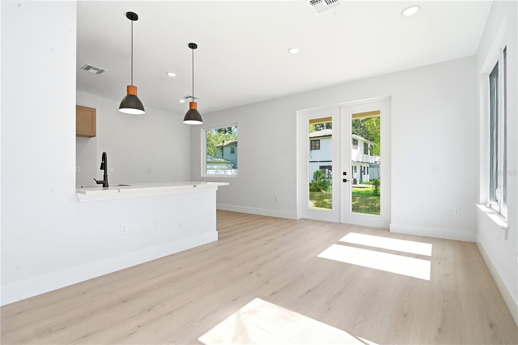 A bright kitchen and living area with light wood floors, pendant lights, and French doors — 1232 VIRGINIA DRIVE, ORLANDO, FL