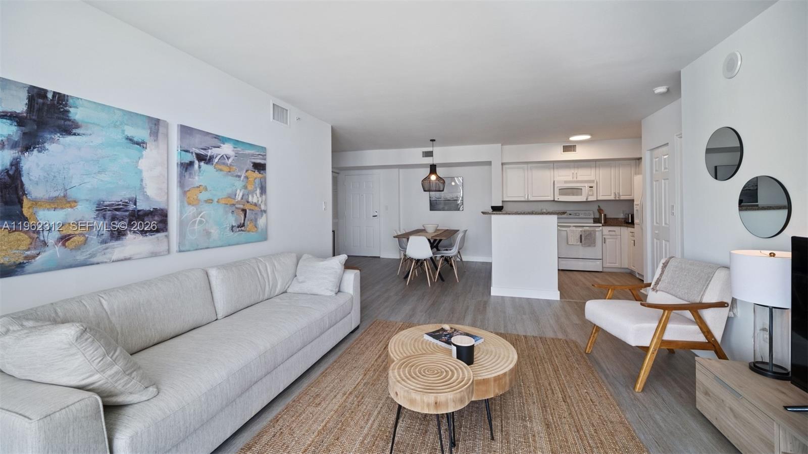 A living room and dining area with light wood floors, white walls, and modern furniture — 1155 Brickell Bay Dr # 2203, Miami FL 33131, MIAMI, FL