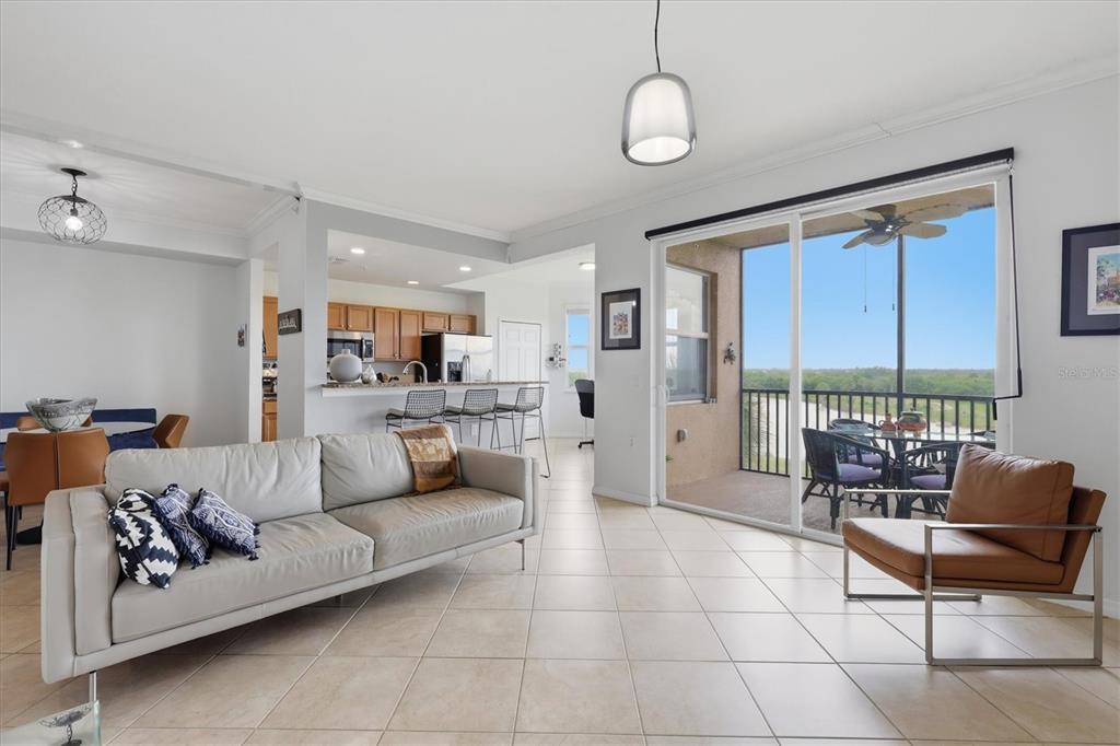 A living room with tile floors, a leather sofa, and a balcony overlooking a landscape — 8309 GRAND ESTUARY TRAIL UNIT 306, BRADENTON, FL