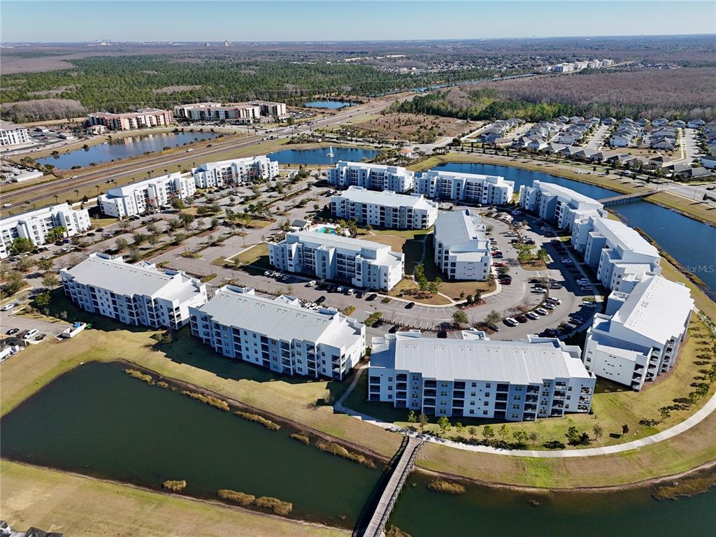 An aerial view shows a multi-building apartment complex surrounded by ponds and parking lots — 3121 PARADOX CIRCLE UNIT 301, KISSIMMEE, FL