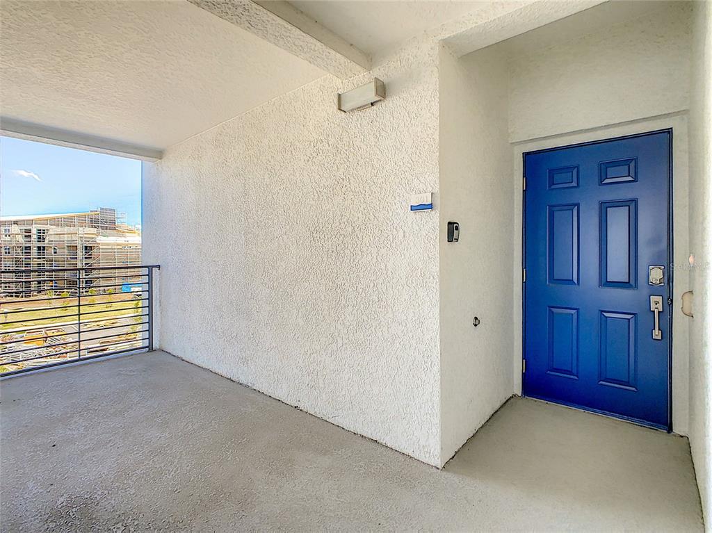 A blue front door opens onto a covered concrete balcony with a metal railing — 3121 PARADOX CIRCLE UNIT 301, KISSIMMEE, FL