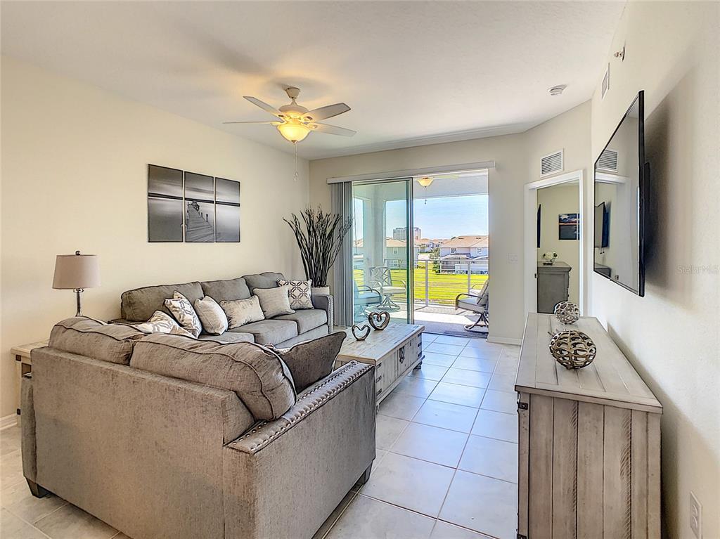 A living room features a grey sofa, a wooden coffee table, and a sliding glass door — 3121 PARADOX CIRCLE UNIT 301, KISSIMMEE, FL