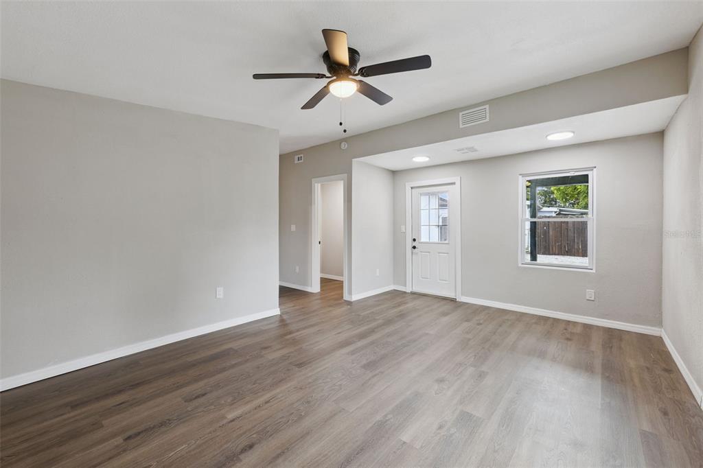An empty room with light gray walls, wood-look flooring, a ceiling fan, and a door — 1061 BIANCA DRIVE NE, PALM BAY, FL