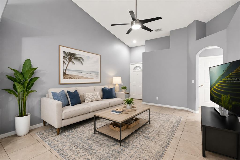 A living room features a beige sofa, a coffee table, and a ceiling fan — 2832 OSPREY COVE PLACE UNIT 202, KISSIMMEE, FL