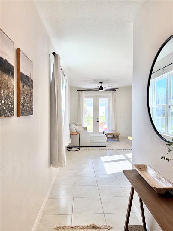 A hallway with tile flooring leads to a living room featuring a sectional sofa — 639 ALDER LANE, AUBURNDALE, FL