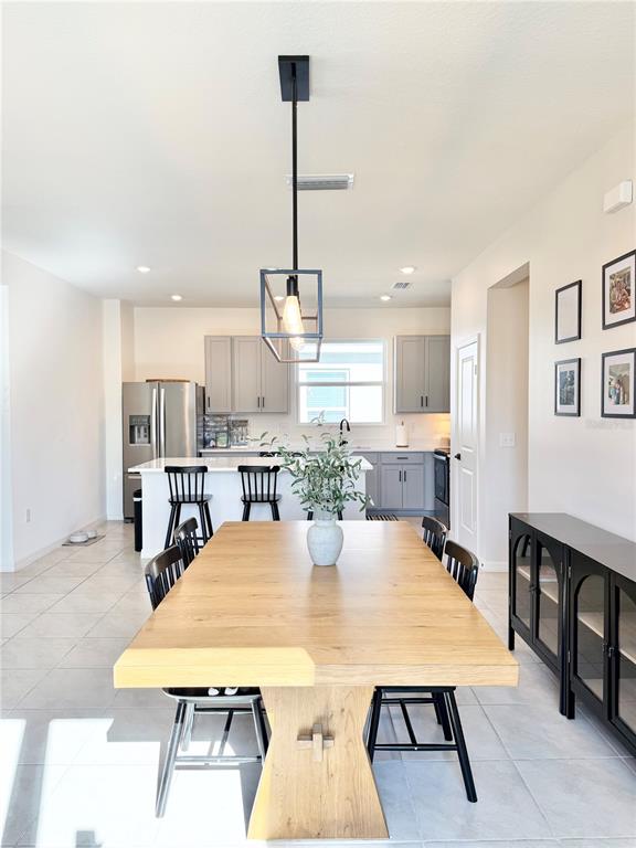 A dining area with a light wood table and black chairs sits before a kitchen — 639 ALDER LANE, AUBURNDALE, FL