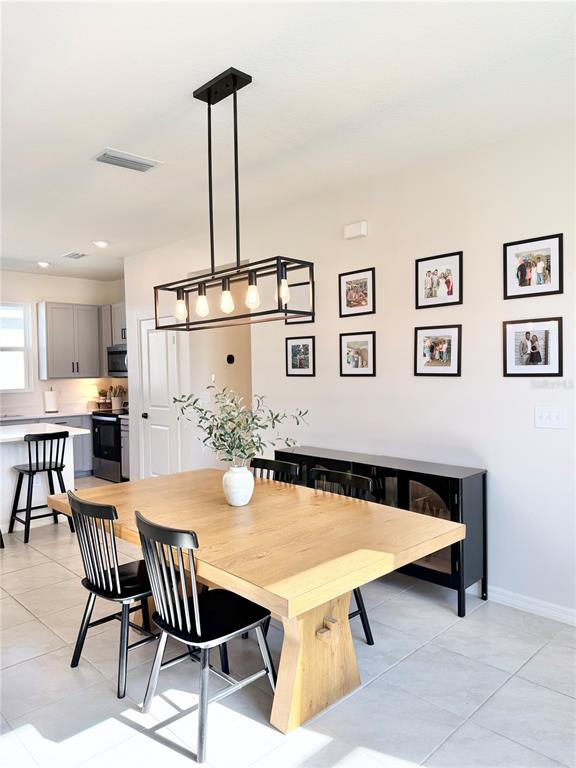A dining area features a wooden table, black spindle chairs, and a rectangular pendant light — 639 ALDER LANE, AUBURNDALE, FL