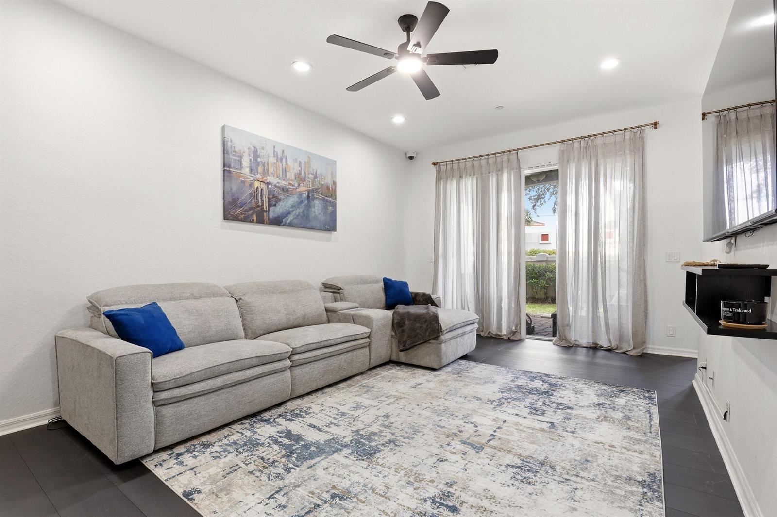 A living room features a gray sectional sofa, a patterned rug, and sliding glass doors — 80 Nottingham Place, Boynton Beach FL 33426, BOYNTON BEACH, FL