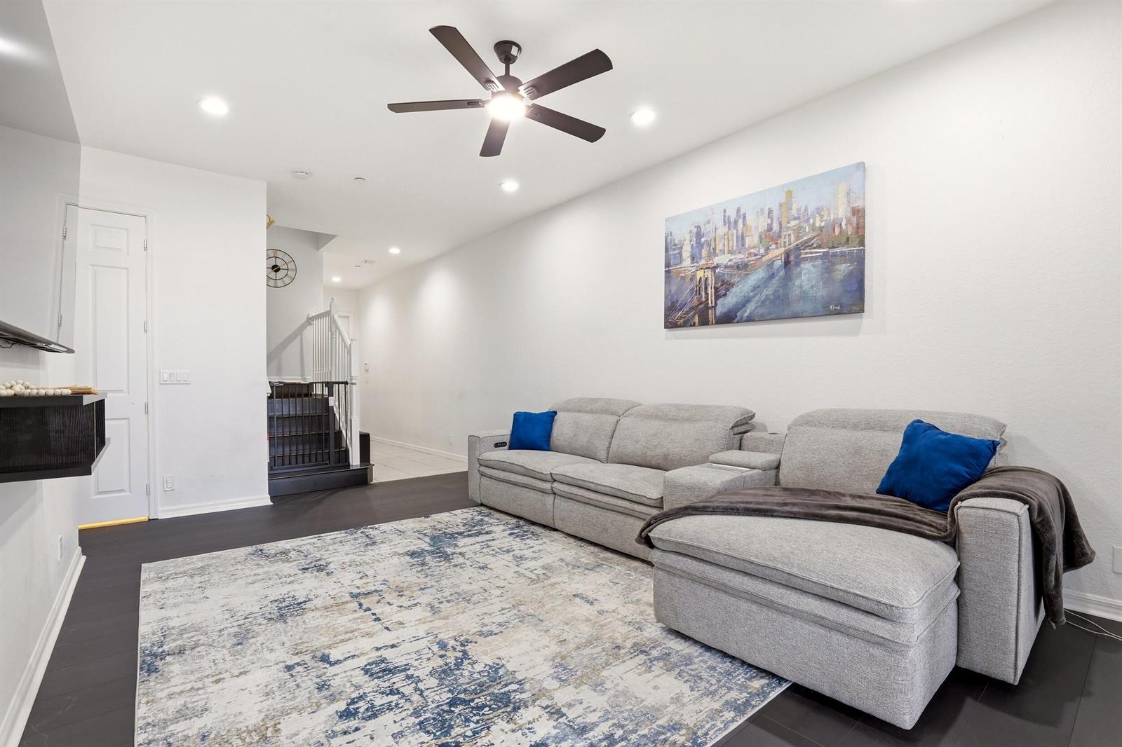 A living room features a grey sectional sofa, a patterned rug, and a city painting — 80 Nottingham Place, Boynton Beach FL 33426, BOYNTON BEACH, FL