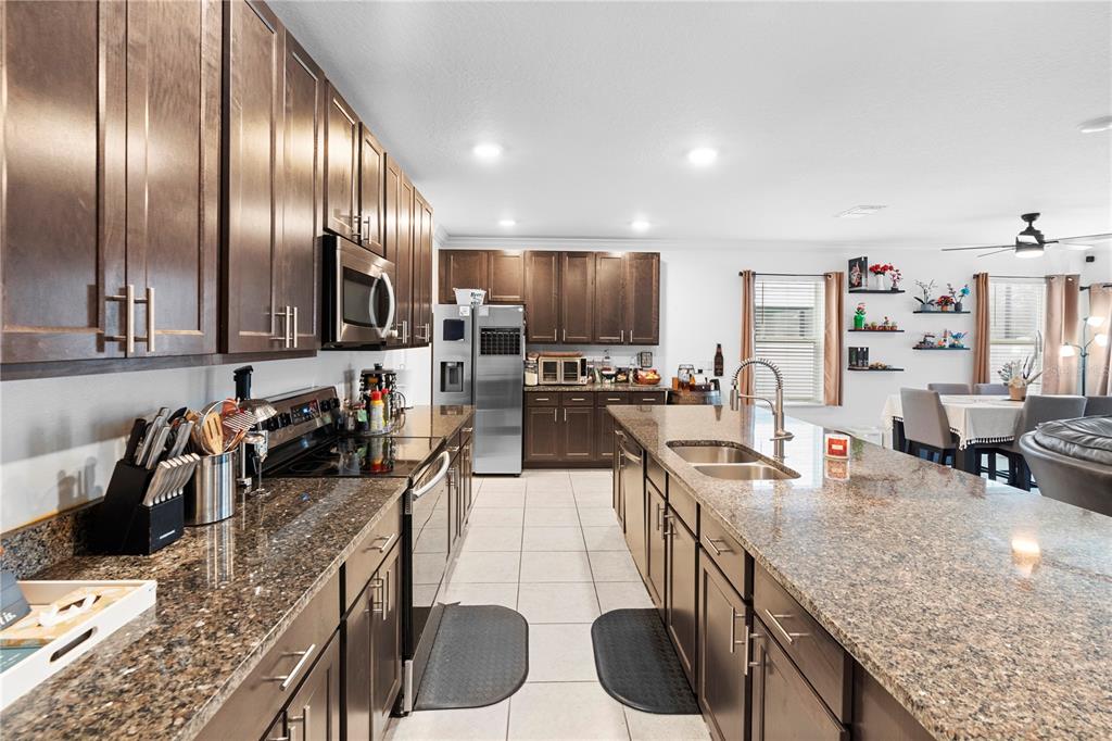 A kitchen featuring dark wood cabinets, granite countertops, a central island, and stainless steel appliances — 164 E FIESTA KEY LOOP, DELAND, FL