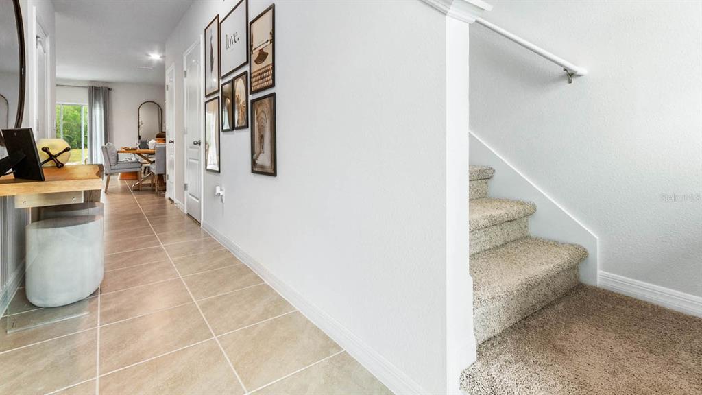 A hallway with tile flooring leads to a dining area, with carpeted stairs on the right — 1604 SWAN SWIM DRIVE, DAVENPORT, FL