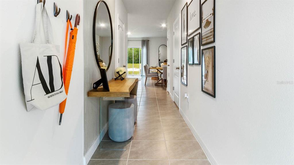A hallway features a wooden console table, a mirror, wall art, and tiled flooring — 1604 SWAN SWIM DRIVE, DAVENPORT, FL