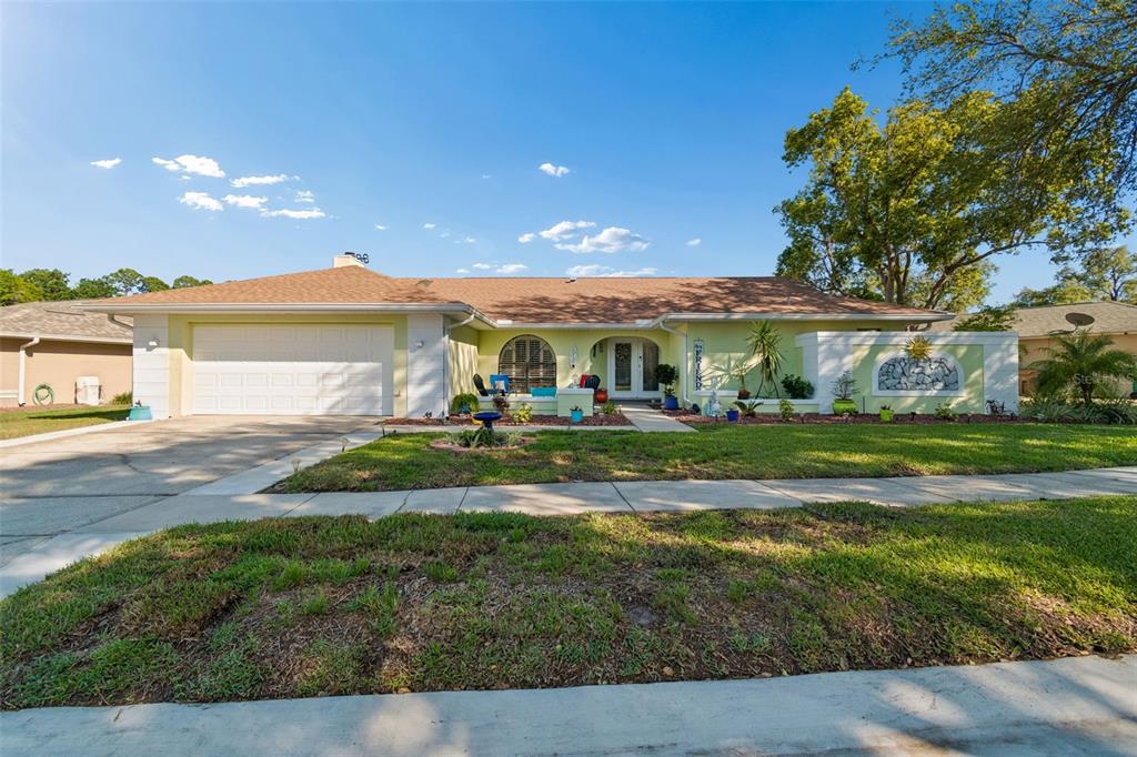 A single-story house with a light green exterior, a two-car garage, and a front lawn — 8930 BROOKER DRIVE, NEW PORT RICHEY, FL