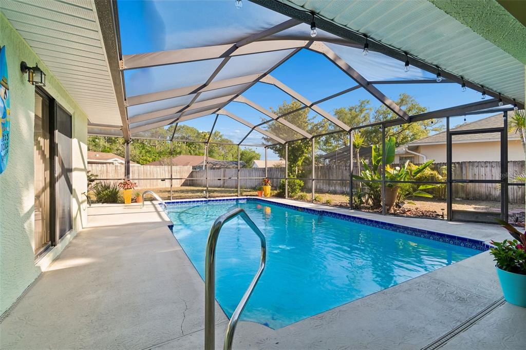 A screened-in swimming pool with a concrete deck and a fenced backyard — 8930 BROOKER DRIVE, NEW PORT RICHEY, FL